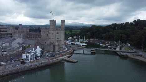 Ancient-Caernarfon-castle-Welsh-harbour-town-aerial-view-medieval-waterfront-landmark-orbiting-right-shot
