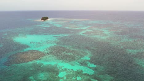 Luftaufnahme-Der-Schönen-Kleinen-Korallenriffinsel,-Umgeben-Von-Sand-Und-Tiefblauem-Ozean,-Der-Sich-Bis-Zum-Horizont-Erstreckt