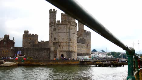 Historic-Caernarfon-castle-Welsh-medieval-harbour-waterfront-town-landmark-dolly-left-through-railings