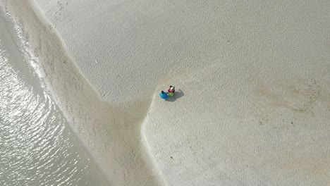 Aerial-top-down-view-of-romantic-couple-walking-on-a-beach-on-their-date,-husband-and-wife-walking-holding-hands