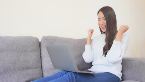 Junge-Asiatische-Frau,-Die-Auf-Laptop-Tippt-Und-Erfolg-Mit-Ja-handgeste-Feiert