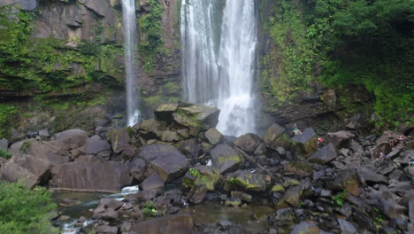 Aerial-pushing-forward-of-man-standing-at-base-of-Nauyaca-waterfall-Costa-Rica