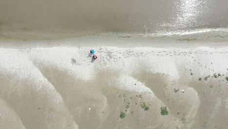 Old-husband-and-wife-walking-on-beach-after-retirement,-old-age-plans,-aerial-top-down-view