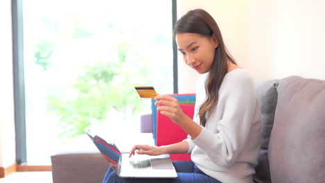 Gastfamilie-Asiatische-Frau,-Die-Online-Mit-Laptop-Computer-Und-Kreditkarte-Einkauft,-Vollbild-In-Zeitlupe