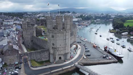 Ancient-Caernarfon-castle-Welsh-harbour-town-aerial-view-medieval-waterfront-landmark-misty-mountains-background