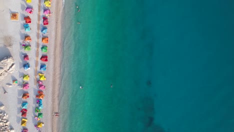 Playa-Con-Sombrillas-De-Colores-Cerca-Del-Agua-Turquesa-Limpia-Del-Mar-Mediterráneo,-Vacaciones-De-Verano