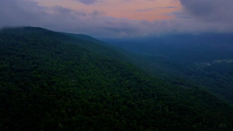 Foggy,-cloudy,-aerial-drone-video-footage-of-nightfall-in-the-Appalachian-Mountains,-during-summer,-with-the-afterglow-of-sunset-still-in-the-background