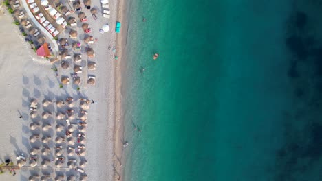 Paradiesstrand-Mit-Sonnenschirmen-Und-Weißem-Sand,-Der-Von-Türkisfarbenem-Meerwasser-In-Albanien-Umspült-Wird