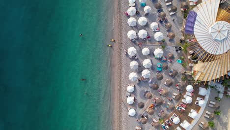 Beach-umbrella-and-bar,-turquoise-sea-water-washing-shoreline-of-Mediterranean-coast-in-Albania