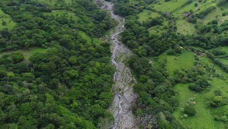Aerial-pans-up-on-remote-mountain-river-valley-in-highlands-of-Costa-Rica,-4K