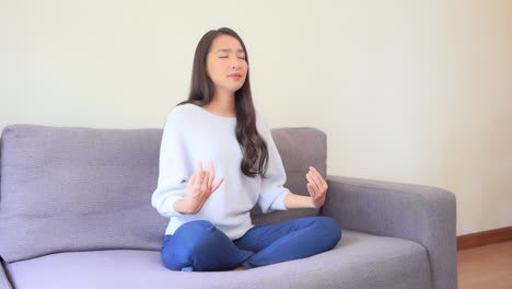 Hübsches-Asiatisches-Mädchen,-Das-Entspannendes-Yoga-Zu-Hause-Auf-Dem-Sofa-Slomo-Praktiziert
