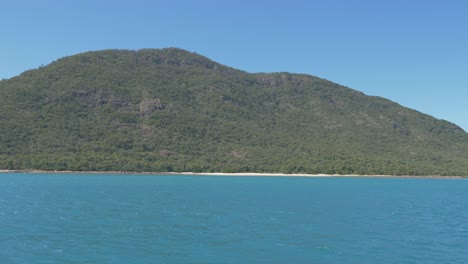 Passing-the-green-mountain-Shaw-Island-on-a-bright-perfect-sunny-day--Queensland,-Australia--Wide