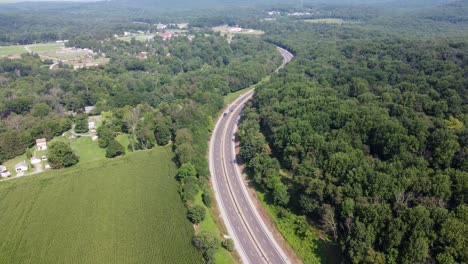 An-aerial-view-of-vehicles-driving-on-a-divided-highway-in-the-tree-covered-countryside
