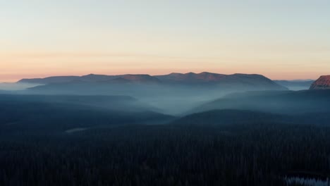Schöne-Linke-Lkw-drohnenaufnahme-Des-Atemberaubenden-Wilden-Uinta-Wasatch-Cache-National-Forest-In-Utah-Mit-Großen-Kiefern-Darunter-Und-Atemberaubenden-Bergen,-Die-Während-Eines-Sommersonnenaufgangs-Mit-Nebel-Bedeckt-Sind