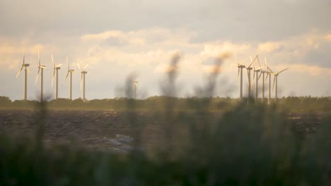 Wind-blowing-and-powering-the-windmills-along-the-riverside,-renewable-clean-and-green-energy,-Öland,-Sweden