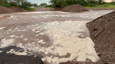 Closeup-of-foam-and-brown-water-during-flash-flood-in-Arizona,-Pima-County