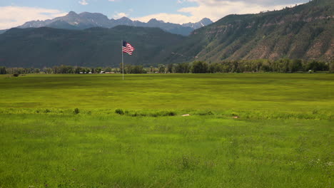 Große-Amerikanische-Flagge-Weht-Anmutig-Im-Wind-über-Einem-Grasfeld-Mit-Den-San-Juan-Mountains-Im-Hintergrund