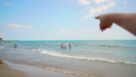 A-woman's-hand-pointing-towards-sea-beach