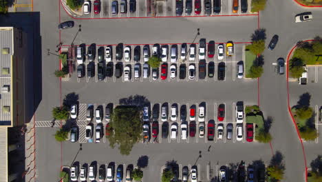 Aerial-top-down-view-of-shopping-center-parking-lot,-people-and-cars-in-carpark-searching-for-spaces,-drone-4K
