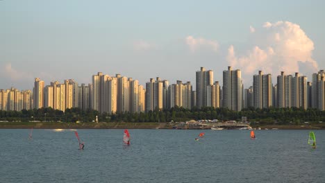 Koreans-Windsurfing-on-Han-river-at-Colorful-Pink-Sunset-on-Complex-Skyscraper-Apartment-Background,-Ttukseom-Surfing-club,-daytime-static