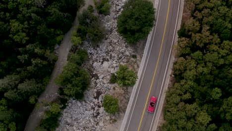 Aerial-Bird's-Eye-View-of-Red-Convertible-Driving-on-Mountain-Canyon-Road