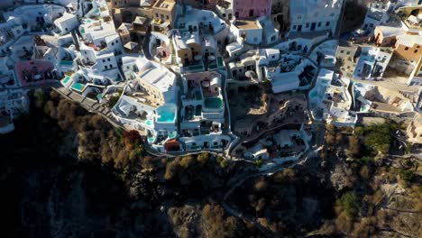 Detailed-close-aerial-top-down-view-of-Oia-with-white-cave-houses-and-villas-revealing-luxury-lifestyle-in-Santorini,-Greece