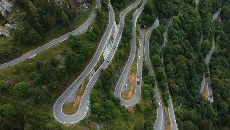 Aerial-drone-above-the-scenic-mountain-serpentine-road-Paluzza-Plöckenpass-in-Italy-by-the-natural-Austrian-alps-in-summer-with-green-forest-trees-in-nature-and-travel-vacation-cars-on-the-street