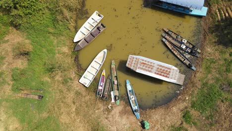 An-aerial-steady-footage-of-a-Boat-Tour-in-Bueng-Boraphet,-Nakhon-Sawan,-Thailand,-revealing-boats-moored-at-a-station-while-a-big-pontoon-is-moving-out