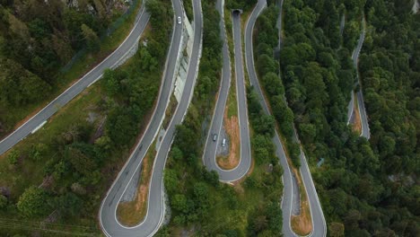 Flying-above-the-scenic-mountain-serpentine-road-Plöckenpass-in-Italy-by-the-natural-Austrian-alps-in-summer-with-green-forest-trees-and-cars-on-the-street