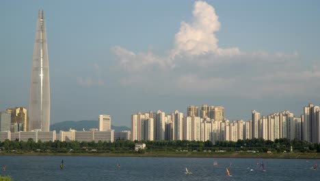 Koreans-Windsurfing-on-Han-river,-Lotter-Tower-on-Background-at-summer-day-static-copy-space