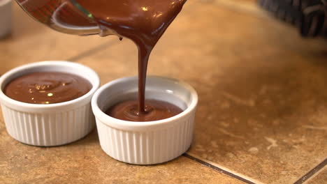 Pouring-individual-homemade-portions-of-chocolate-pot-de-crème-into-individual-serving-cups---slow-motion