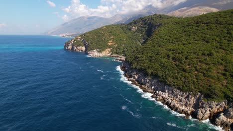 Schöne-Küste-Im-Mediterranen-Albanien,-Meereswellen,-Die-Auf-Felsen-Die-Grünen-Hügel-Hinunterspritzen