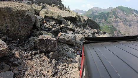 Rooftop-of-4WD-vehicle-following-another-on-narrow-trail-cut-in-mountain-side-high-above-Poughkeepsie-Gulch-in-Colorado