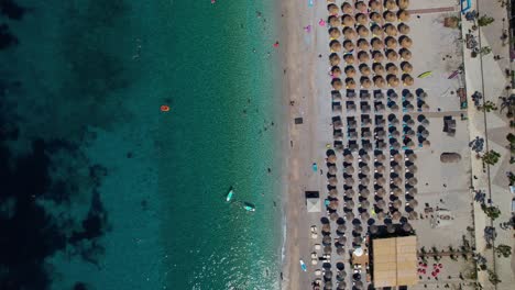 Clean-beach-on-seaside-of-Albania-in-Mediterranean-sea-with-umbrellas-near-emerald-seawater