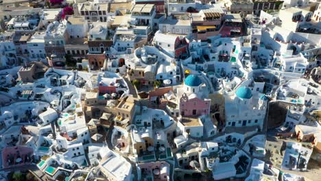 Detailed-close-aerial-of-Oia-with-white-cave-houses-and-villas-revealing-luxury-lifestyle-in-Santorini,-Greece