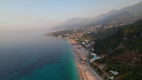 Strand-Von-Dhermi-Mit-Sonnenschirmen-Und-Resorts-An-Der-Küste,-Die-Von-Blauem,-Türkisfarbenem-Meerwasser-Umspült-Werden