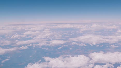 Flying-over-the-clouds,-view-from-the-plane-on-a-blue-sky-and-cumulus-clouds