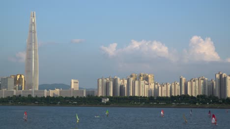 A-Group-of-men-is-windsurfing-at-Han-river-near-Lotter-tower-daytime,-Jamsil-district-of-Seoul-city,-South-Korea