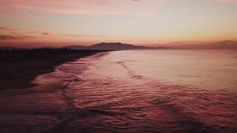 Aerial-low-angle-above-tidal-waves-crashing-at-calm-beach-in-Mexico-at-dusk