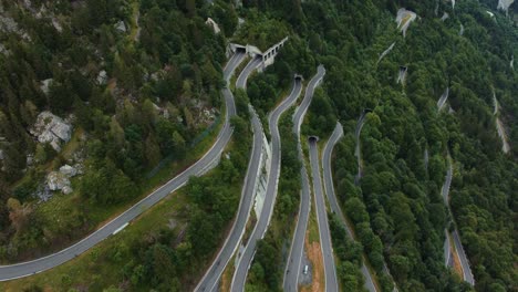 Aerial-view-drone-flight-above-the-scenic-mountain-serpentine-road-Plöckenpass-in-Italy-by-the-natural-Austrian-alps-in-summer-with-green-forest-trees-in-nature-and-travel-vacation-cars-on-the-street
