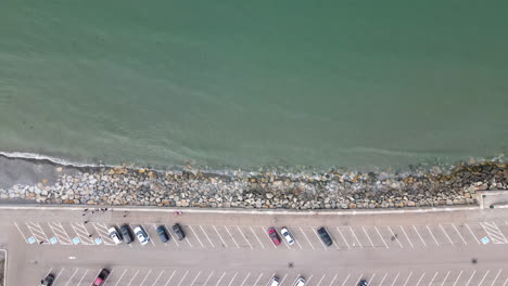 Aerial-descent-over-parking-lot-and-sea-wall,-Nantasket-Beach,-MA