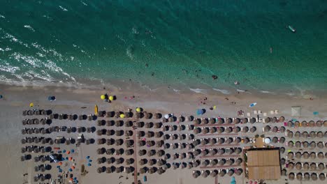 People-sunbathing-on-beach-full-of-umbrellas-and-swimming-on-clean-emerald-sea-water-in-Albania