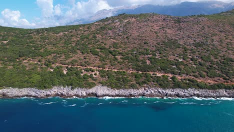 Mediterranean-seaside-in-Albania-with-rocky-coastline-and-green-hills-washed-by-blue-sea-water