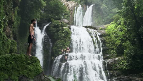 Man-stands-in-front-of-Nauyaca-waterfalls-Costa-Rica-with-leaves-in-foreground
