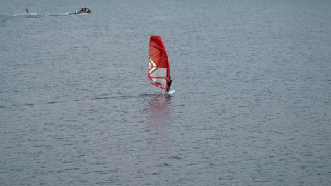 One-person-windsurfing-at-Han-river-on-sunset,-near-Ttukseom-Park-surfing-club,-Seoul,-South-Korea,-static-distant-view
