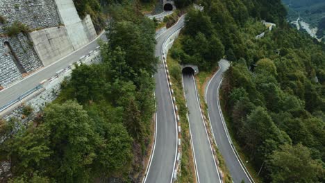 Flying-above-the-idyllic-mountain-serpentine-road-Plöckenpass-in-Italy-by-the-natural-Austrian-alps-in-summer-with-green-forest-trees-and-cars-on-the-street