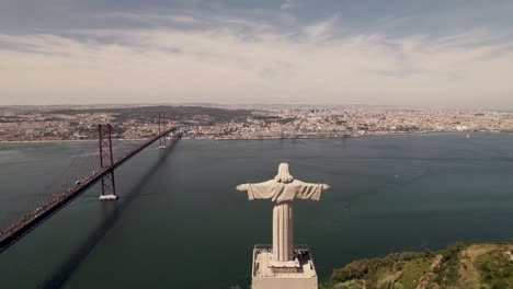 Aerial-fly-over-Cristo-rei,-Christ-the-King-Sanctuary,-view-Lisbon-riverside-cityscape