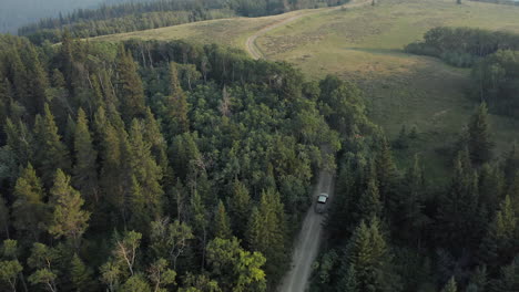 Truck-driving-on-winding-gravel-country-road-amongst-woodland-trees