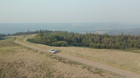 Aerial,-White-Pick-Up-Truck-Driving-Off-Road-In-Aspen-Parkland-Grassland
