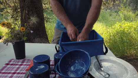 Caucasian-male-washing-dishes-at-campgrounds;-tedious-chore